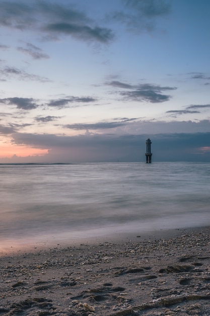 Free photo vertical shot of  lighthouse in the middle of the sea