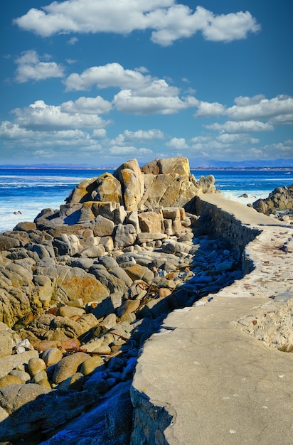 Vertical shot of a lot of rock formations on the beach under the beautiful cloudy sky