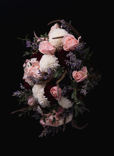 Vertical shot of a luxurious bouquet of pink roses and white, red dahlias on a black