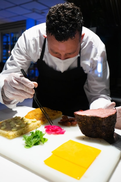 Free Photo vertical shot of a male chef wearing a face mask preparing a delicious meal