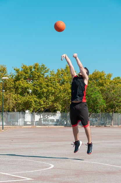 Vertical shot of a male throwing the basketball ball in a court