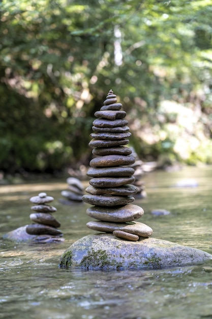 Free photo vertical shot of many stone pyramids balanced on a river water