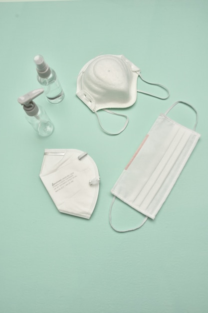 Vertical shot of medical masks and bottles of disinfectant on a blue table