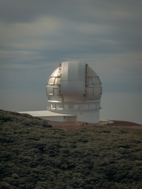 Vertical shot of an observatory building on a mountain near a grassy field