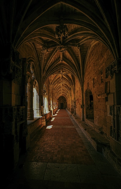 Vertical shot of an old building's hallway with windows and a door in the distance