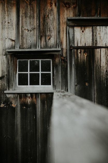 Free Photo vertical shot of an old wooden shed with a small white window