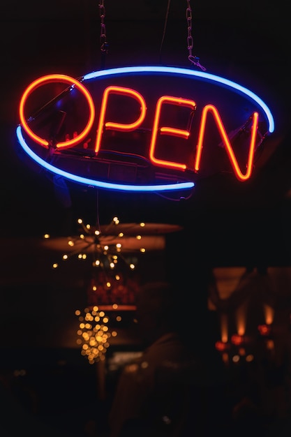 Free Photo vertical shot of an orange and blue neon sign that says "open" at a bar