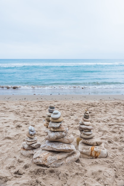 Free photo vertical shot of pebbles stacked on each other in a balance at the beach