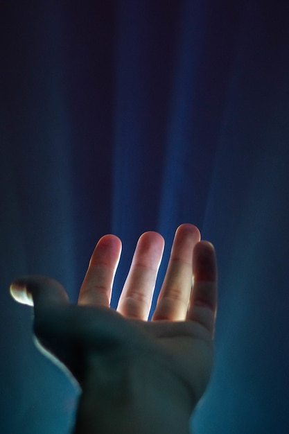 Vertical shot of a person's hand with a light shining through the fingers