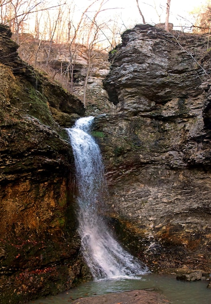 Vertical shot of a powerful waterfall flowing through rocks in a forest