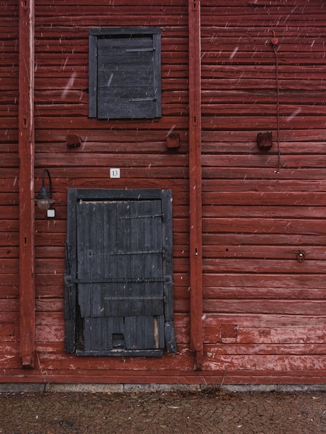 Free Photo vertical shot of a red wooden wall with gray wooden doors in winter