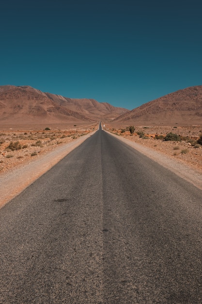 Vertical shot of a road in the middle of the desert and mountains captured in Morocco