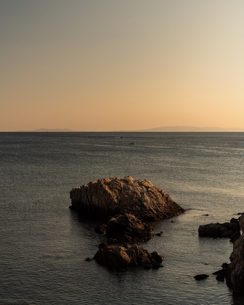 Vertical shot of rocks of different sizes in the sea under the clear sky