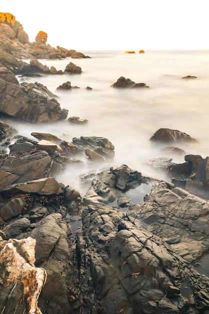 Free photo vertical shot of rocks immersed into the ocean in vapour form in menorca. islas baleares. spain