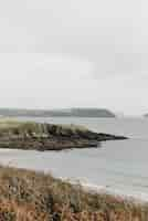 Free photo vertical shot of a rocky cliff by the sea under a cloudy sky