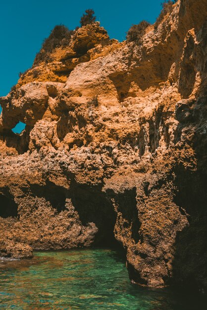 Vertical shot of a rocky cliff reflecting on the sea on a sunny day