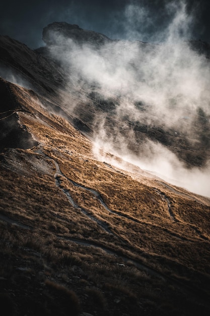 Vertical shot of rocky mountains covered with clouds