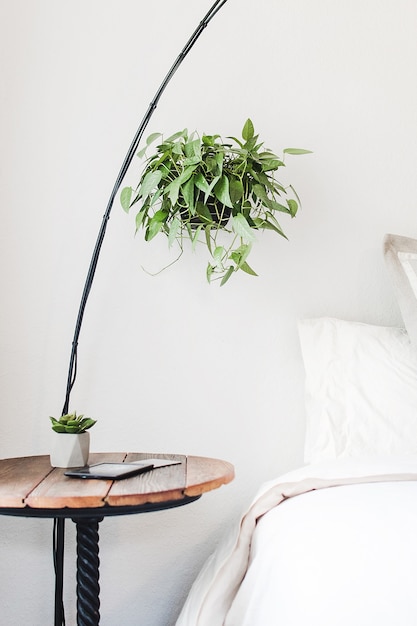 Vertical shot of a round brown side table beside a bed