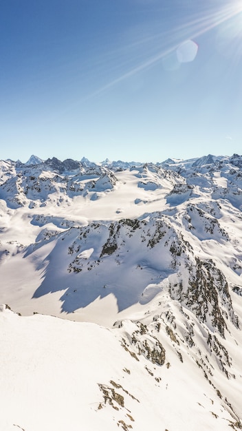 Vertical shot of a scenic mountain peak covered in snow during the day.