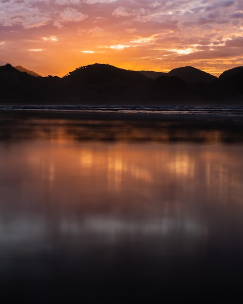 Vertical shot of the sea with mountains in the distance at sunset