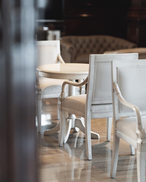 Vertical shot of simple white chairs and tables in a restaurant with a blurry background