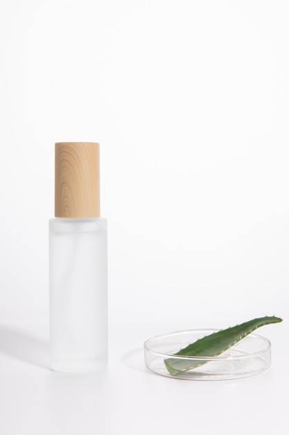 Vertical shot of a single skincare bottle next to a plate with aloe ver