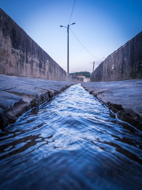 Free photo vertical shot of a small canal through cement walls on both sides