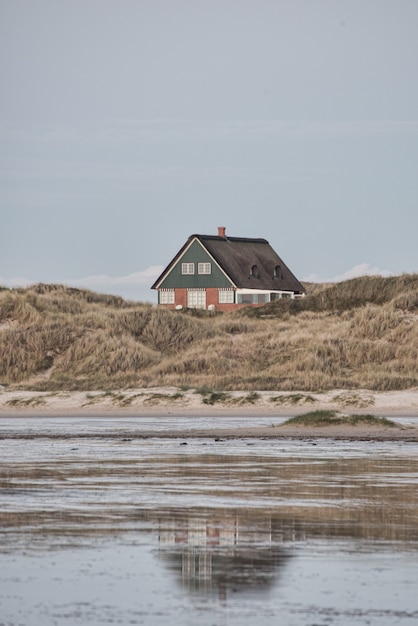 Free photo vertical shot of a small isolated house on the shore of the sea