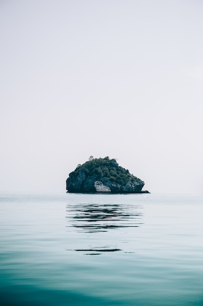 Free photo vertical shot of a small rocky island in the middle of the ocean captured in thailand