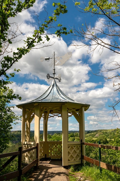 Vertical shot of a small tower in front of a forest under a cloudy sky