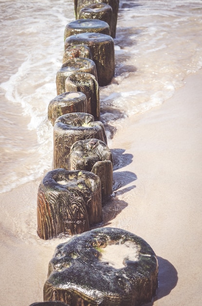 Free photo vertical shot of small wooden planks on a sandy shore