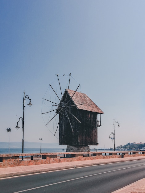 Vertical shot of a small wooden windmill on the side of the road in the countryside