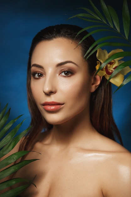 Vertical shot of smiling beautiful woman with flower in hair.