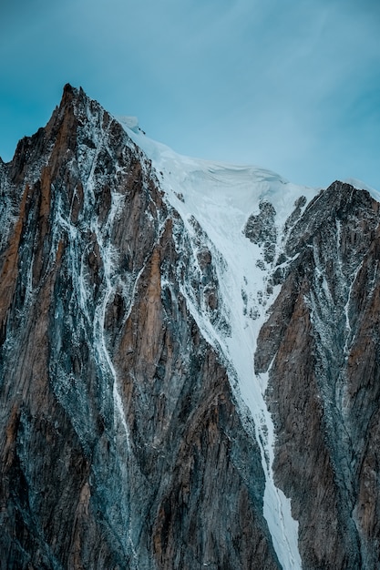 Vertical shot of a snowy mountain with a clear sky in the background