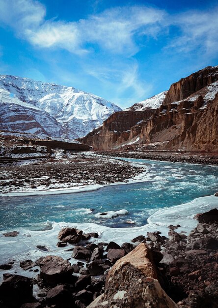 Vertical shot of Spiti valley in winter with frozen river and snow peak mountains