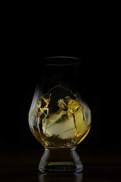 Vertical shot of a splashing golden coloured liquid in a glass isolated