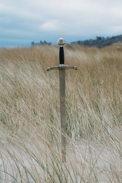 Vertical shot of a sword in the sandy beach