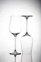 Free photo vertical shot of two empty wineglasses on the white surface with shadows, one is upside down