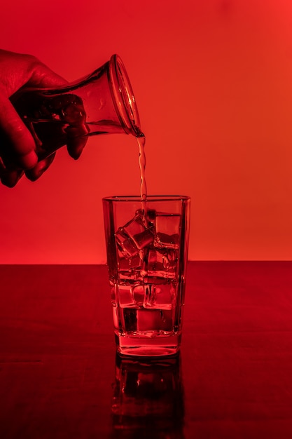 Vertical shot of two glasses of ice water in red light