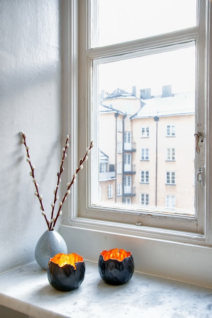 Free Photo vertical shot of two unique candle holders and a vase with a houseplant near the window