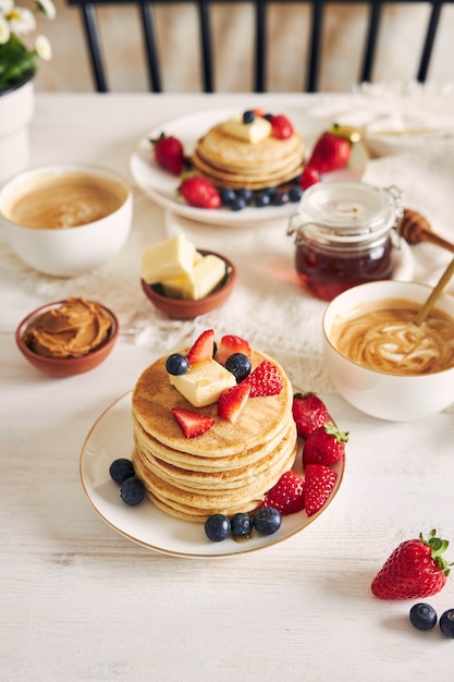 Vertical shot of vegan tofu pancakes with fruits near syrup and coffee