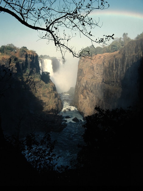 Free photo vertical shot of a water stream in the middle of cliffs and a waterfall in the distance