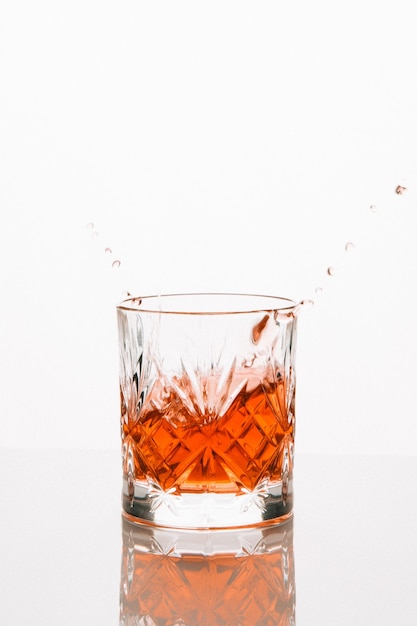 Free photo vertical shot of a whiskey glass reflecting on the table