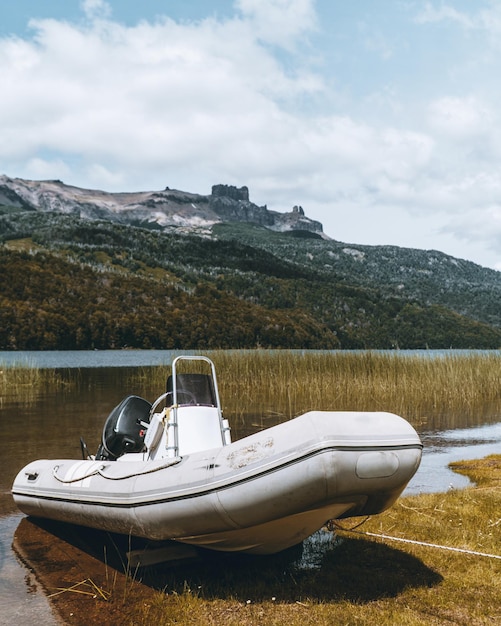 Free Photo vertical shot of a white boat parked in the lake with a mountain in the background