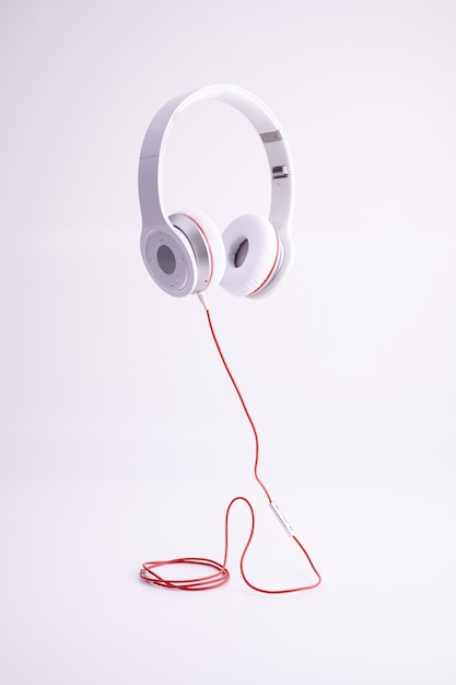 Free photo vertical shot of white headphones with a red cable