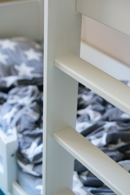 Free photo vertical shot of a white wooden ladder near the bed