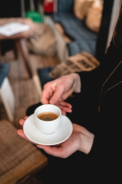 Vertical shot of a woman holding a cup of espresso