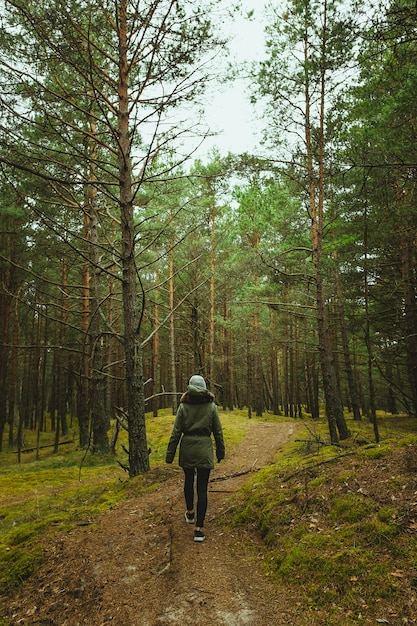 Vertical shot of a woman walking through the forest