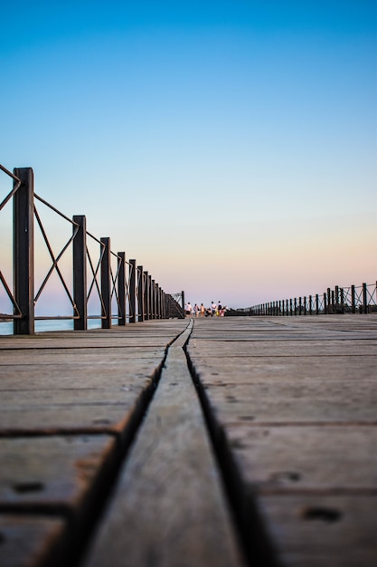 Free photo vertical shot of a wooden dock surrounded by fences under the blue sky in the evening