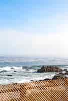 Free photo vertical shot of a wooden fence near a rocky shore and a sea